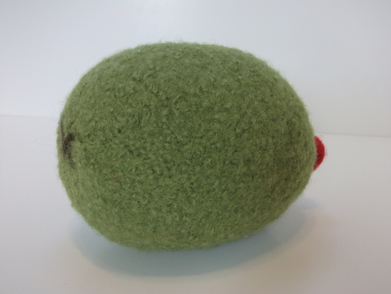 May include: A green felt ball with a red felt accent. The ball is soft and fuzzy.