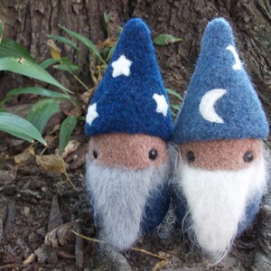 May include: Two small, blue felt gnome figures with white stars and a crescent moon on their hats. They have white felt beards and brown felt faces.