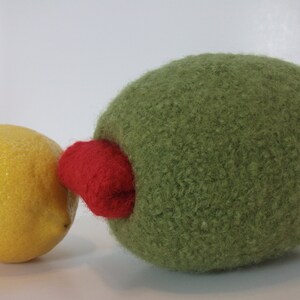 May include: A green felt ball with a red felt patch on the side, next to a yellow lemon.