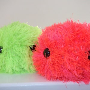 May include: Two fuzzy, plush toys with large black eyes. One toy is bright green and the other is bright pink.