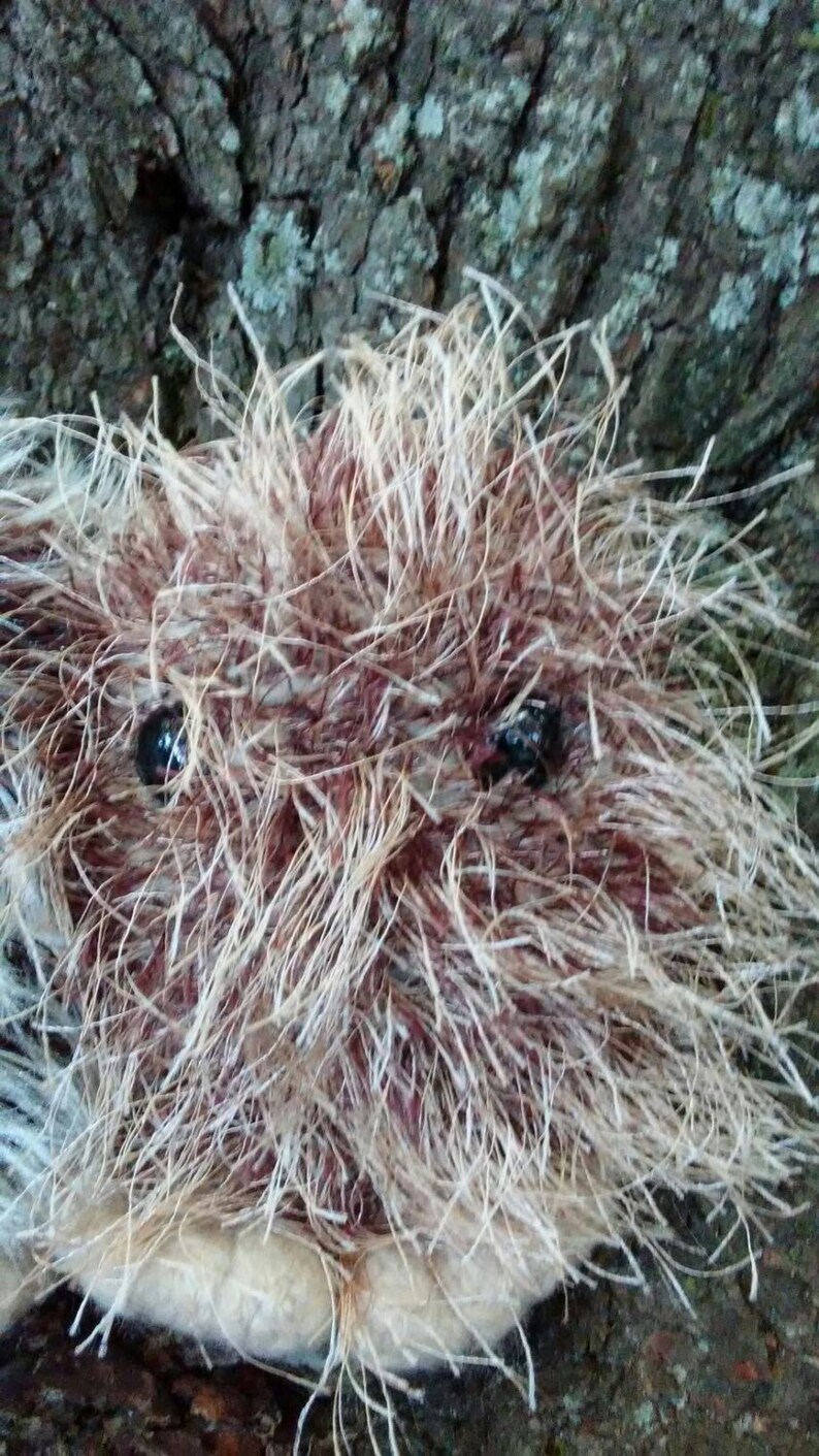 May include: Close-up of a fluffy, brown and white stuffed animal with black button eyes. The animal is lying on a rough, textured surface.