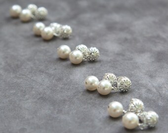 May include: Five pairs of pearl earrings with silver filigree accents. The earrings are arranged in a row on a gray surface.