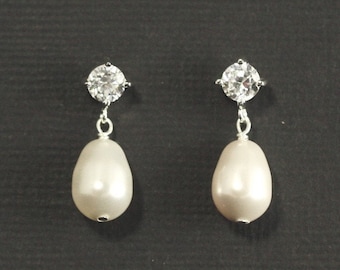 May include: A pair of silver earrings with a clear crystal stone and a white pearl drop.