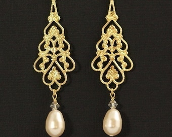 May include: Gold filigree dangle earrings with a pearlescent drop. The earrings feature a delicate, intricate design with a gold finish.
