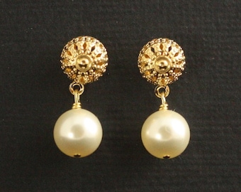 May include: A pair of drop earrings featuring a gold-toned filigree stud top with a spherical, cream-colored faux pearl dangling from a small gold jump ring. The intricate metalwork on the stud displays a textured, perforated pattern.