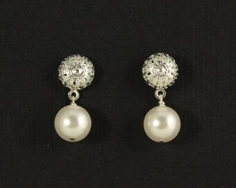 May include: A pair of drop earrings featuring a silver-toned filigree stud top with a spherical, openwork design. Each stud is connected to a smooth, round, white pearl-like bead that hangs vertically from a small silver-toned jump ring.