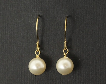 May include: A pair of drop earrings featuring round, cream-colored faux pearls suspended from gold-toned metal hooks. Each pearl is attached to the hook with a small gold-toned wire loop, creating a simple, dangling design that hangs vertically.