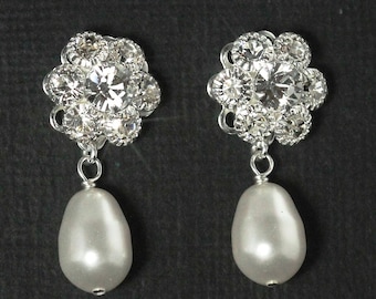 May include: A pair of silver earrings with a cluster of clear rhinestones and a single white pearl drop.