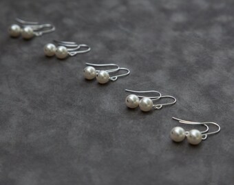 May include: Four pairs of pearl earrings with silver hooks. The pearls are white and round.