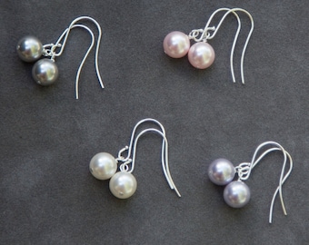 May include: Four pairs of pearl earrings with silver hooks. The earrings are in shades of gray, white, and pink.