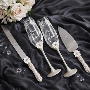 Personalized white wedding toasting set with 3D flowers, engraved champagne flutes, white wedding glasses, floral wedding glass set, sculpted flower decor glasses, custom wedding flutes with names, elegant white wedding accessories, cake knife and server white set, floral handled wedding knife server, romantic wedding toast glasses, bride groom toasting flutes, custom wedding glassware, white floral wedding decor, handmade wedding toasting set, wedding reception accessories white