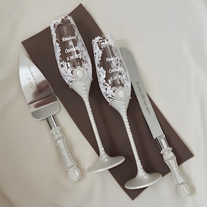 May include: A wedding set featuring two champagne flutes and two serving utensils. The flutes and utensils have white pearl accents and are engraved with names and a date. The text on the knife reads "It was always you."
