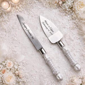 May include: A silver cake knife and server set with handles decorated in white pearls. The knife blade is engraved with the text "Siempre Juste tu" and the server blade is engraved with the text "Dunia & Edgar February 14, 2026".