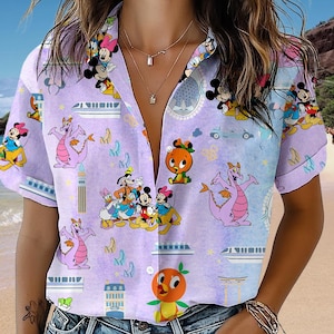 May include: A purple and white short-sleeved button-up shirt with a variety of Disney characters, including Mickey Mouse, Donald Duck, Goofy, and a dragon. The shirt has a light blue background with a white collar and buttons.