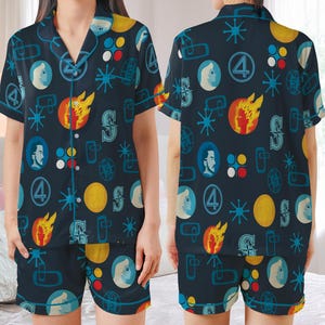 May include: Navy blue pajama set featuring a repeating pattern of comic book imagery. The short-sleeved top and shorts display a design with the number 4, portraits, flames, and starbursts in yellow, blue, red, and white. The top has a button-down front.