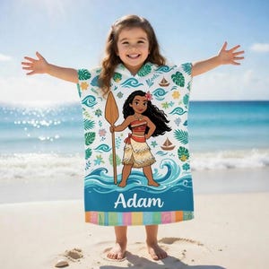 K&ouml;nnte beinhalten: Ein wei&szlig;es und blaues Strandtuch mit Kapuze und einer Cartoon-Illustration einer polynesischen Prinzessin, die ein Paddel h&auml;lt. Das Handtuch hat den personalisierten Namen "Adam" unten aufgedruckt. Das Handtuch ist mit Wellen, Booten und tropischen Bl&auml;ttern verziert.