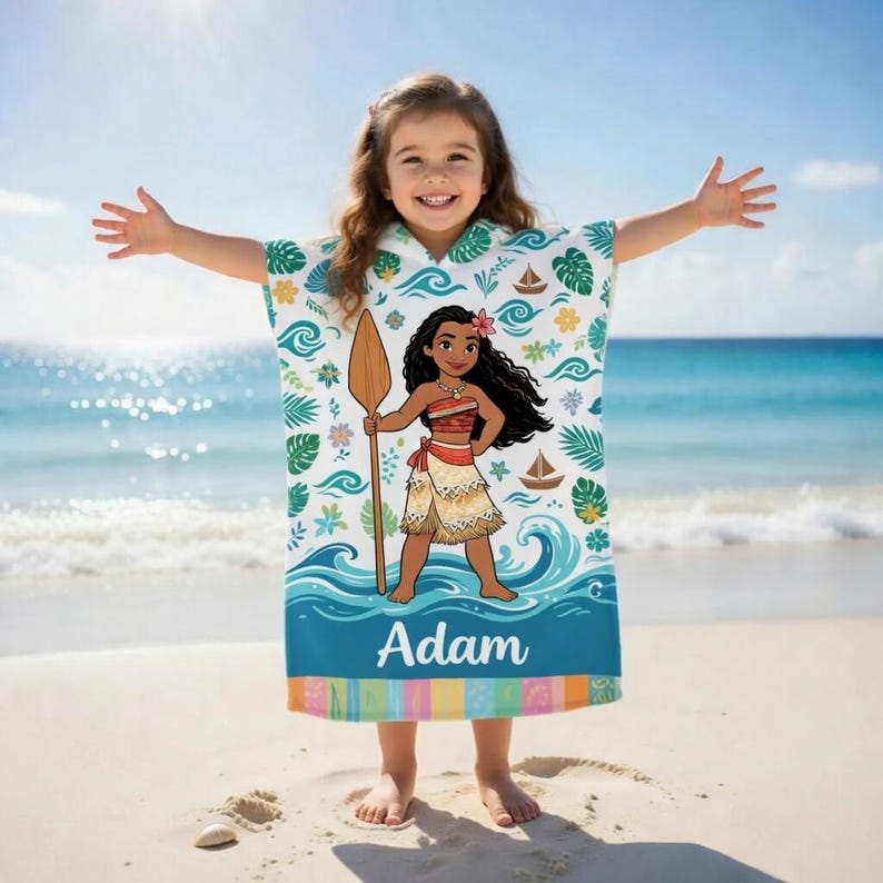 K&ouml;nnte beinhalten: Ein wei&szlig;es und blaues Strandtuch mit Kapuze und einer Cartoon-Illustration einer polynesischen Prinzessin, die ein Paddel h&auml;lt. Das Handtuch hat den personalisierten Namen "Adam" unten aufgedruckt. Das Handtuch ist mit Wellen, Booten und tropischen Bl&auml;ttern verziert.
