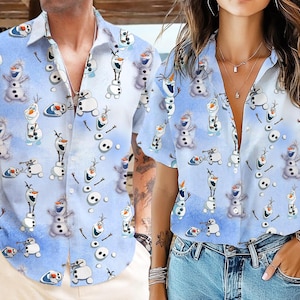 May include: Light blue button-down shirt featuring a repeating pattern of the snowman Olaf from the movie Frozen. The shirt has short sleeves and a classic collar. The background has a gradient effect, transitioning from white to light blue.