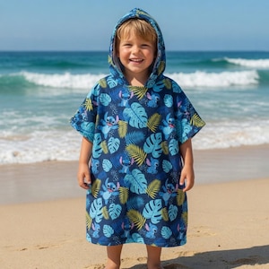 Puede incluir: Un poncho de toalla con capucha en color azul oscuro que presenta un patr&oacute;n repetitivo del personaje Stitch de Lilo y Stitch, intercalado con hojas tropicales de monstera y palmera en azul claro y amarillo, con mangas cortas.
