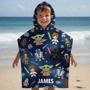 May include: A dark blue hooded poncho towel featuring a repeating pattern of Star Wars characters including Grogu, Luke Skywalker, Darth Vader, R2-D2, C-3PO, and Chewbacca, along with spaceships and lightsabers. The name JAMES is printed in white at the bottom.