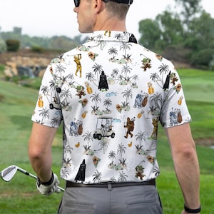 Pu&ograve; includere: Polo da golf bianco con stampa tropicale con personaggi di Star Wars, palme e golf cart. La camicia ha un colletto button-down e maniche corte. La persona nell'immagine indossa la camicia su un campo da golf.