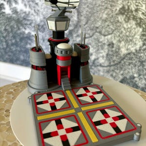 May include: A 3D printed model of a radar tower with a rotating antenna, a red and gray base, and a platform with four black and white squares.