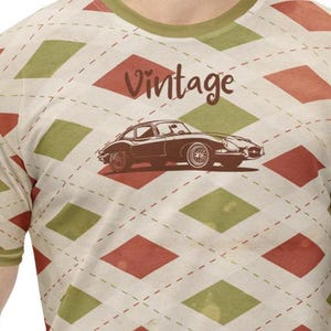 Puede incluir: Una camiseta de estilo vintage con un patrón de rombos marrones y verdes. La camiseta presenta una ilustración en blanco y negro de un coche clásico y la palabra "Vintage" en texto marrón.