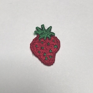 May include: Embroidered strawberry patch with a red body and green stem. The patch features small green seeds and is likely for decorative purposes, such as on clothing or accessories.