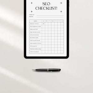 May include: A black and white digital checklist on a tablet screen with the text "SEO CHECKLIST!" at the top. The checklist includes habits such as "Sleep for 7-8 hours", "Drink 8 glasses of water", and "Wake up at 5 AM". There is a checkmark next to the first habit. The checklist is divided into days of the week, with columns for Sunday through Saturday.