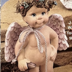 May include: A ceramic cherub figurine with wings, a flower crown, and a pink ribbon around its neck. The cherub is holding a small brown bear figurine. The figurine is 7 inches tall.