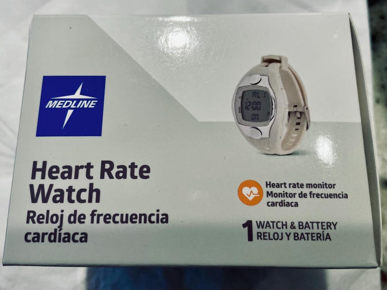 Pu&ograve; includere: Un cardiofrequenzimetro bianco e argento con display digitale &egrave; mostrato su una scatola. La scatola &egrave; bianca con il marchio "MEDLINE" e le parole "Heart Rate Watch" in inglese e spagnolo.