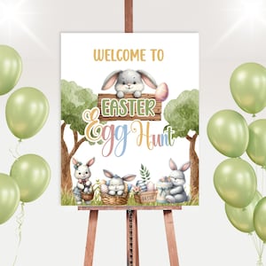 May include: Welcome to Easter Egg Hunt sign with a white background and three bunnies. The sign is on an easel with green balloons in the background.
