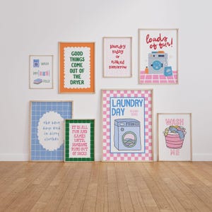 May include: A collection of eight framed wall art prints featuring laundry-themed illustrations and typography. The prints include phrases like 'loads of fun!', 'laundry today or naked tomorrow', and 'good things come out of the dryer' in colorful, graphic designs.