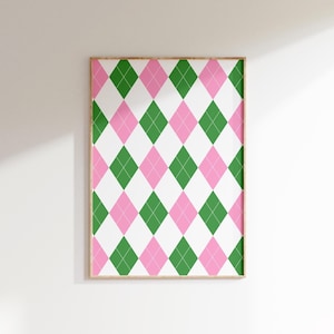 Può includere: Una stampa incorniciata con un motivo a rombi ripetuto. Il design è composto da diamanti verdi e rosa su sfondo bianco. La cornice è in legno chiaro e la stampa è esposta su una parete bianca.