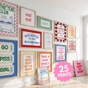 May include: A collection of twenty-five rectangular wall art prints in light wood frames, featuring various colourful graphic designs and humorous text related to bathroom decor, including phrases like The Tub Club, Welcome to the Bathroom, and Wash Your Hands.