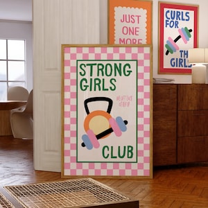 Può includere: Un poster verticale incorniciato con un bordo a scacchi rosa e bianco. Il testo centrale recita STRONG GIRLS CLUB in verde, con WE LIFT EACH OTHER UP in un testo rosa più piccolo. Sono illustrati una kettlebell arancione e un manubrio blu e rosa.