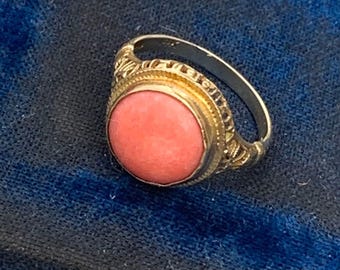 May include: A gold ring with a pink stone set in a decorative bezel. The ring has a delicate filigree design.