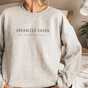 May include: Gray sweatshirt with the text "ORGANIZED CHAOS but mostly just chaos."