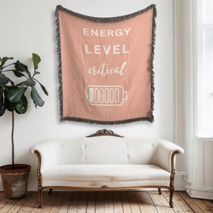 Könnte beinhalten: Eine rosa gewebte Wand-Tapete mit dem Text "ENERGY LEVEL critical" und einem Batteriesymbol mit einem leeren Ladestrich.