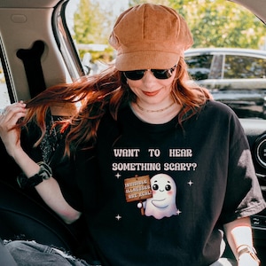 May include: A black t-shirt with a white ghost graphic and the text "Want to hear something scary? Invisible allergies are real."