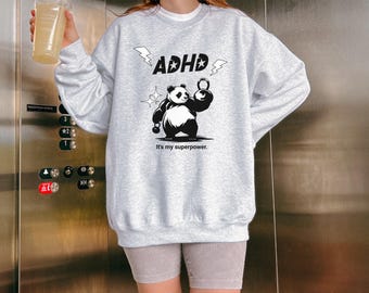 May include: Grey sweatshirt featuring a black and white panda lifting a weight. The text "ADHD" is above the panda and the text "It's my superpower." is below the panda.