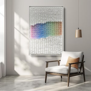 Può includere: Una grande opera d'arte murale rettangolare con una cornice trasparente. L'opera presenta un gradiente di colori, che passa dal rosa al blu, al verde e infine a un arancione caldo. Il resto dell'opera è bianco. Davanti all'opera c'è una moderna sedia con un cuscino bianco e un cuscino marrone.