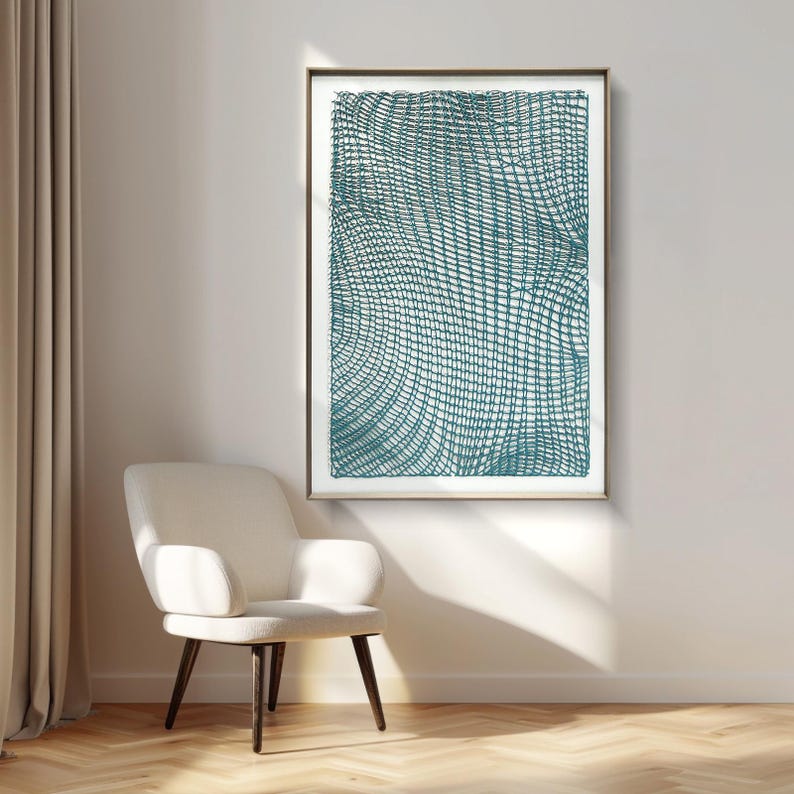 May include: Teal and white abstract art print in a gold frame. The artwork features a grid-like pattern with curved lines, creating a textured effect. The print is displayed on a white wall above a white armchair with dark wooden legs, creating a modern interior design.