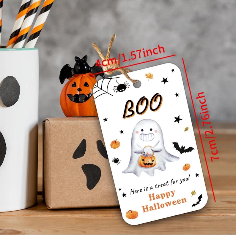 May include: A Halloween gift tag, measuring 7 cm tall and 4 cm wide, featuring a ghost illustration holding a pumpkin. The tag reads "BOO" and "Here is a treat for you! Happy Halloween."