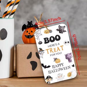 May include: A white Halloween gift tag, 7cm tall and 4cm wide, with the text "BOO HERE'S A TREAT FOR YOU! HAPPY HALLOWEEN". The tag is decorated with Halloween-themed illustrations, including bats, pumpkins, and ghosts.