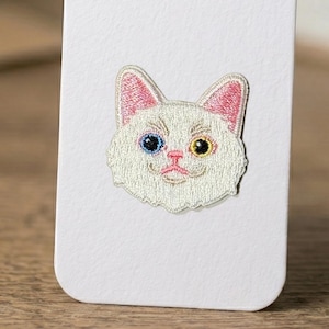 May include: A white ceramic mug with a black handle and the text "But First, Coffee" in a handwritten style. The mug is on a white surface. The mug is approximately 10 cm tall.