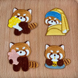 Könnte beinhalten: Vier gestickte Aufnäher mit roten Pandas. Einer hält Blumen, ein anderer ist eine Parodie auf das Gemälde "Mädchen mit dem Perlenohrring", ein dritter hält einen rosa Leckerbissen und der letzte hält ein Getränk.