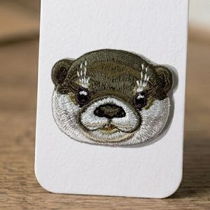 Broderad utterlapp: Glansigt tyg, högdensitetssömmar, strykapplikation