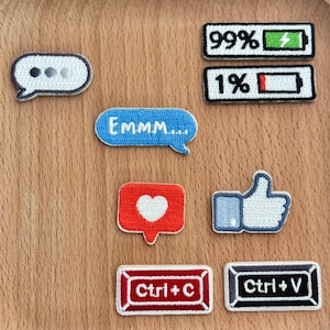 Może przedstawiać: Zestaw haftowanych naszywek z ikonami związanymi z mediami społecznościowymi i technologią. Zawiera dymki, serce, kciuk w górę, wskaźniki naładowania baterii oraz klawisze Ctrl+C i Ctrl+V. Naszywki są w różnych kolorach.