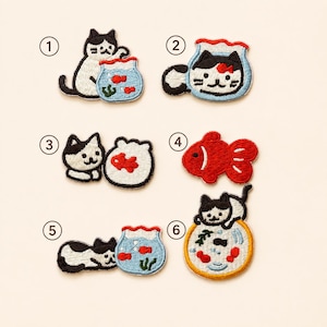 May include: Six embroidered patches featuring black and white cats and goldfish bowls. Number 1 shows a cat by a bowl, 2 a cat in a bowl, 3 a cat and a bowl, 4 a red goldfish, 5 a cat lying by a bowl, and 6 a cat on a yellow-rimmed bowl.